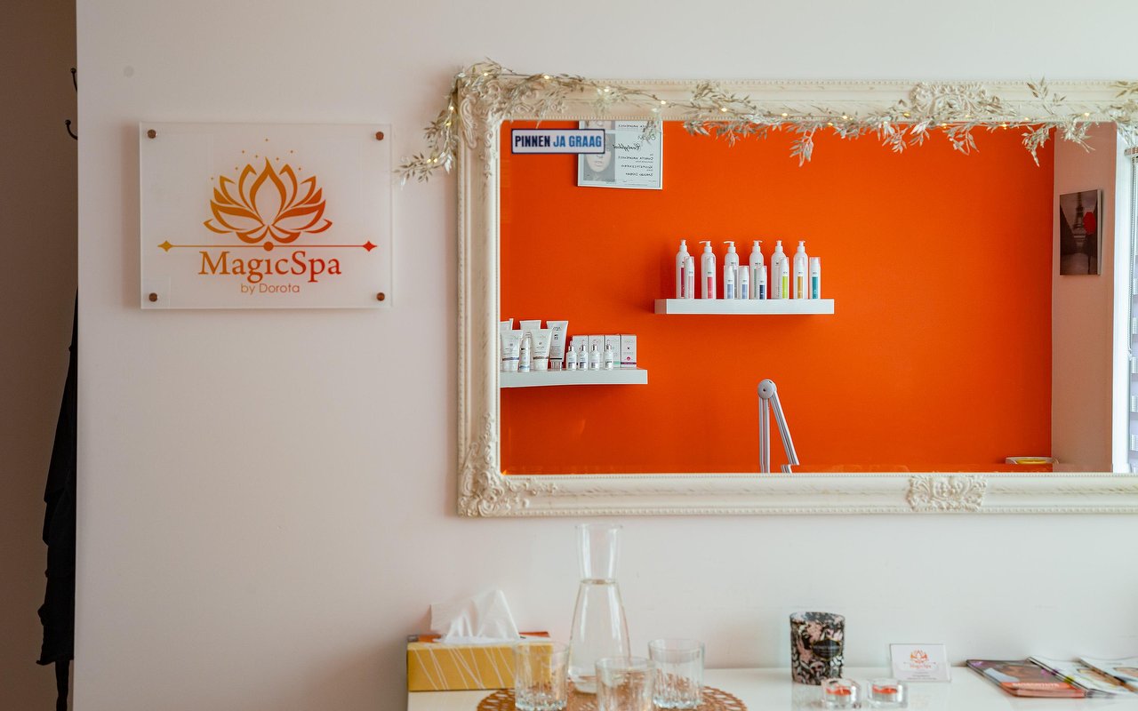 Spiegel met witte sierlijst en het bord met het lotuslogo van MagicSpa
